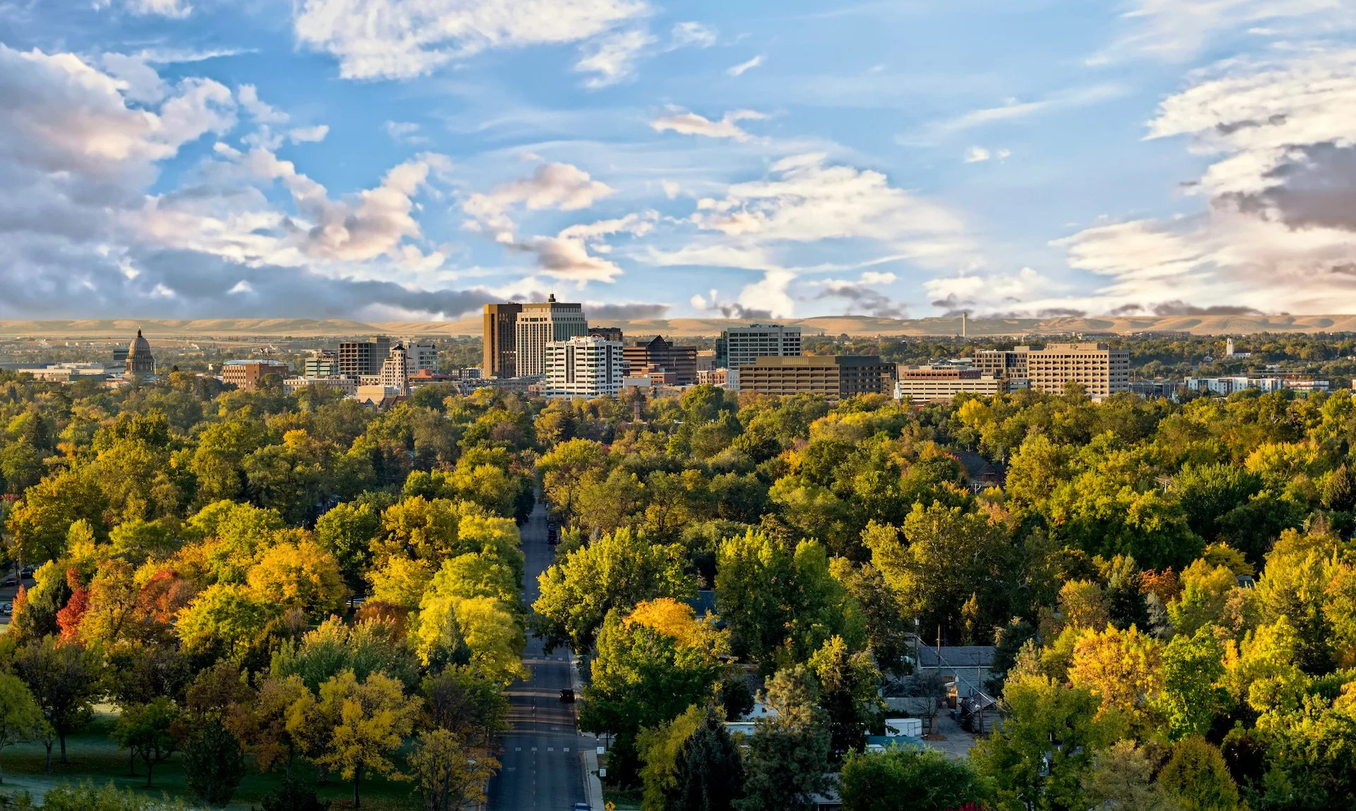 Downtown Boise, Idaho, viewed above tree-lined streets on a partly cloudy autumn day.