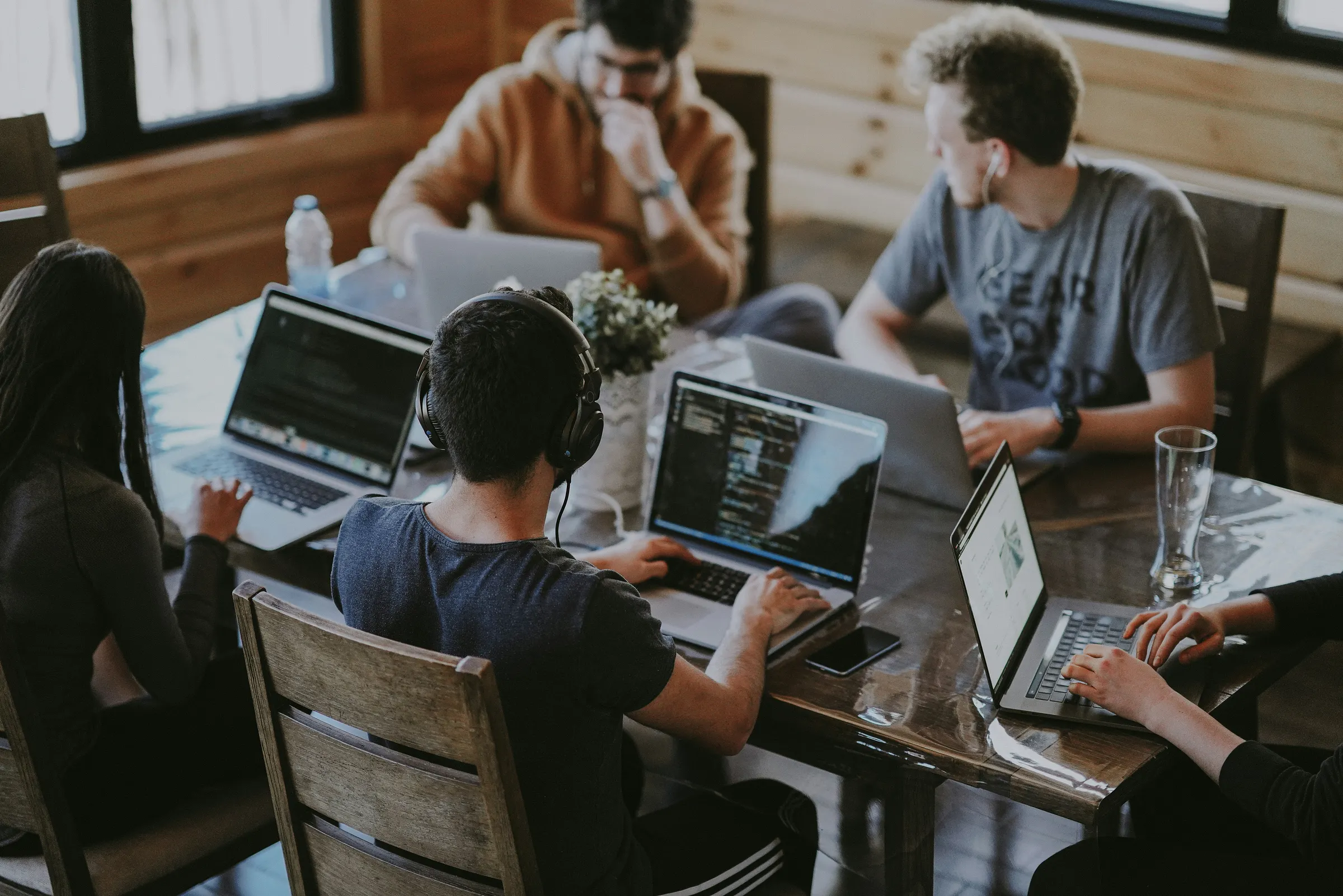 Coworkers collaborate around a table with laptops and notebooks.