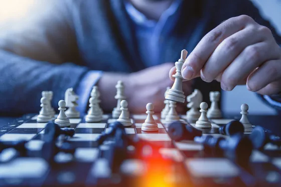 A hand moves a black chess king across a chessboard.