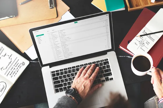 An email inbox is open on a laptop surrounded by desk tools.