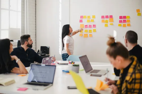 A team discusses ideas in front of a wall covered with notes.