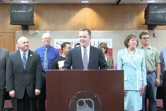 Aaron Klein speaks at a podium with Sierra College leaders behind him.