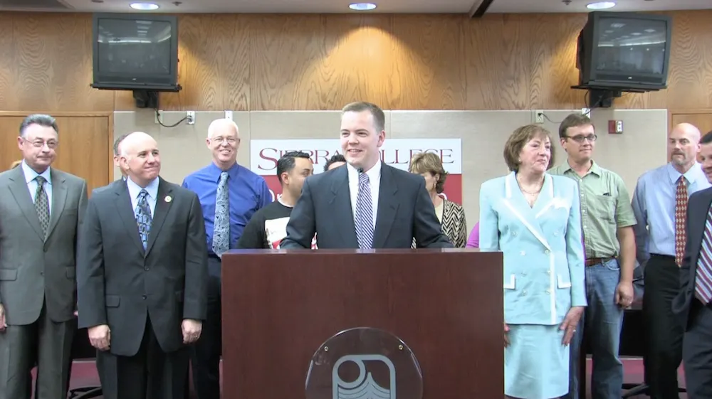 Aaron Klein speaks at a podium with Sierra College leaders behind him.