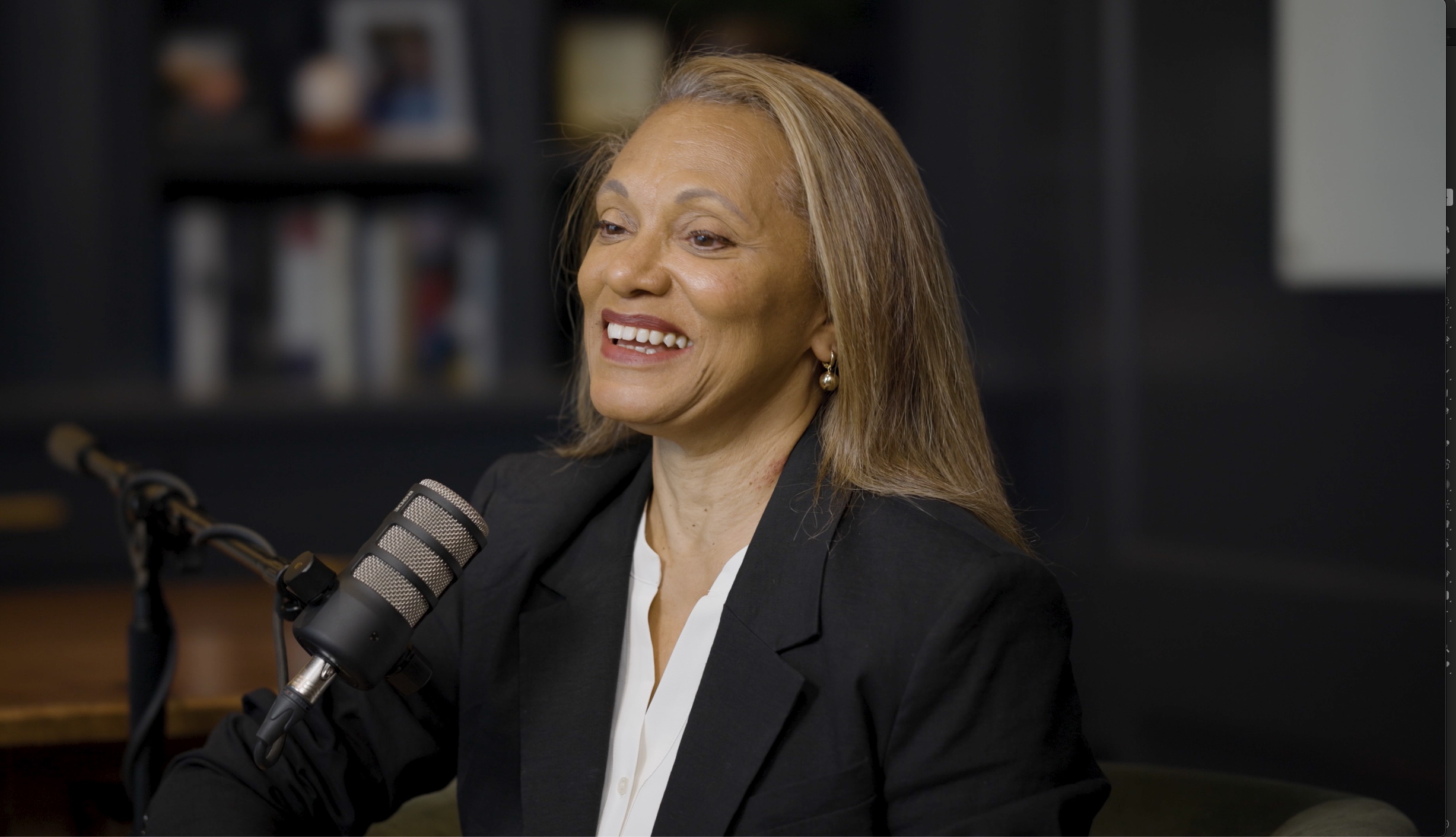 Donna White speaking into a studio microphone during a conversation with Aaron Klein.