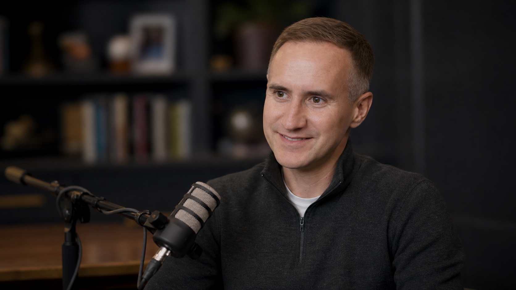 Morgan Housel speaking into a broadcast microphone during a podcast conversation.