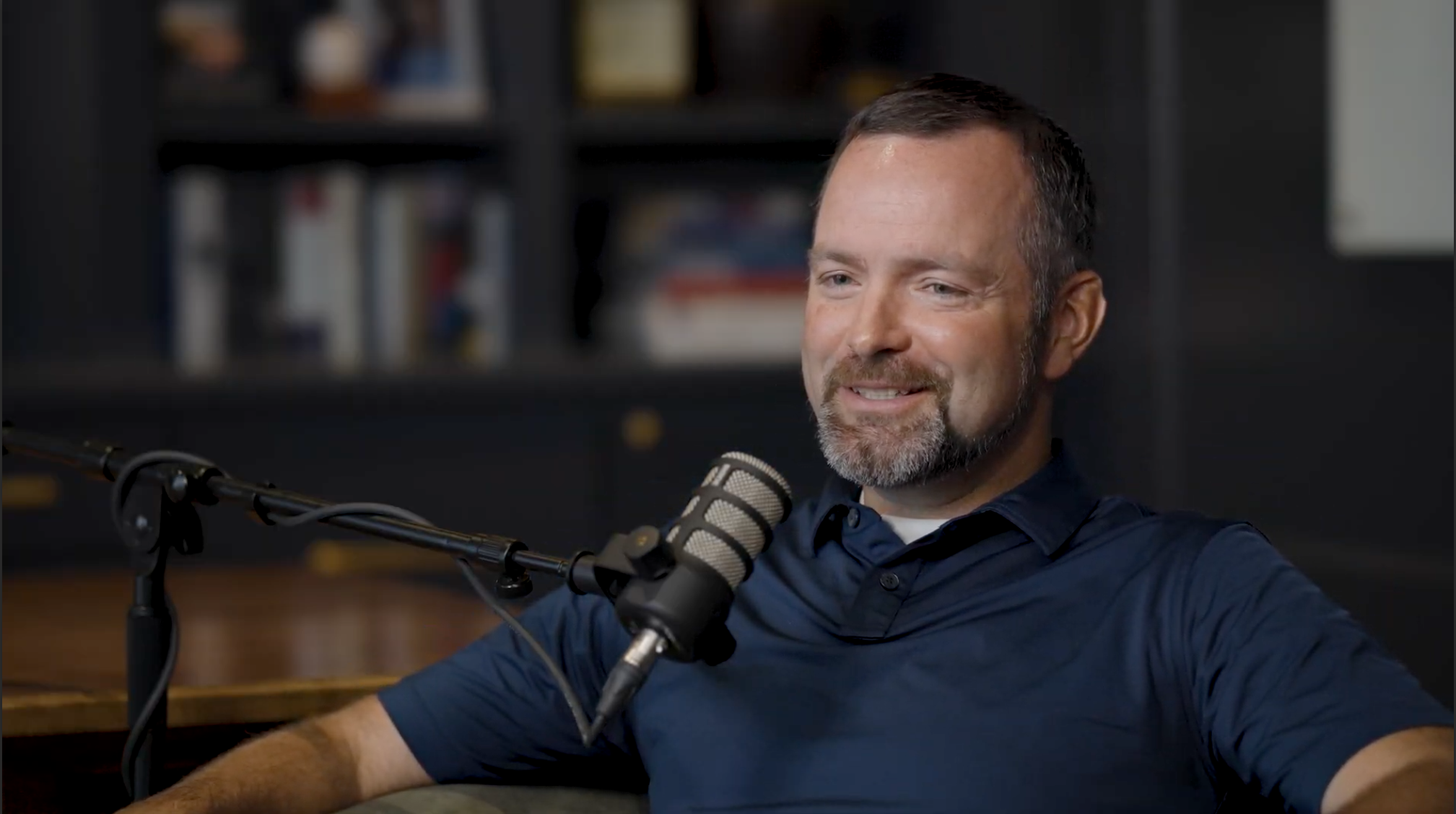 Todd Cranney speaking into a studio microphone during a conversation with Aaron Klein.